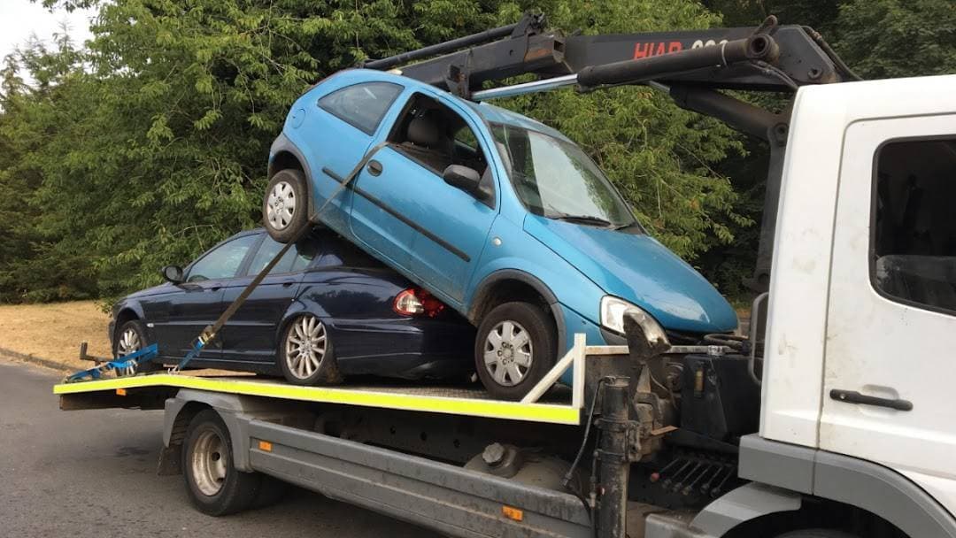 Two cars loaded on a tow truck